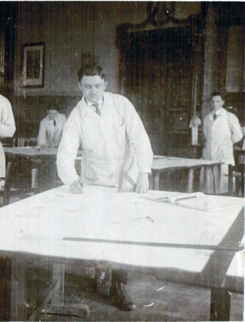 Mann in Werkstatt bearbeitet Zeichnung auf Tisch.